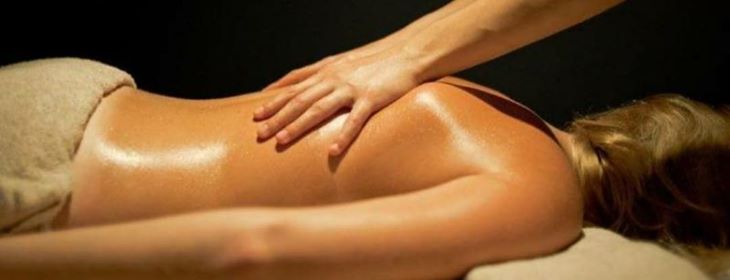 Femme allongée sur le ventre qui reçoit un massage aux huiles